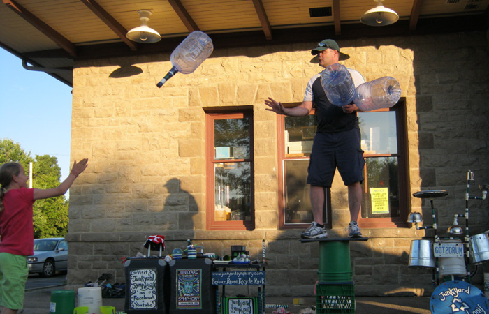 A volunteer tosses a jug to Jonny.