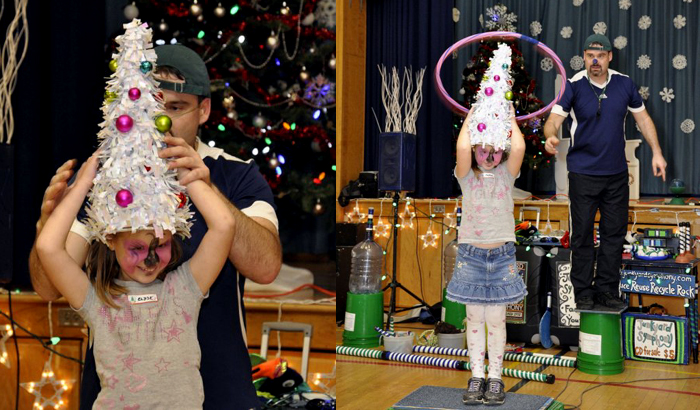 Jonny throws a hoola hoop over a gril dresses as a Christmas tree.